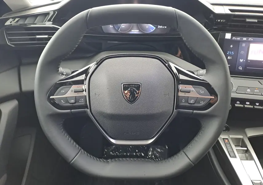 Vue rapprochée du volant noir de la Peugeot 308 2025 avec commandes intégrées et logo lion central.