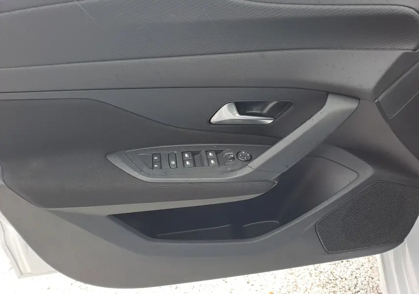 Intérieur de la porte avant gauche de la Peugeot 308 blanc Okenite, avec commandes des vitres et poignée argentée.