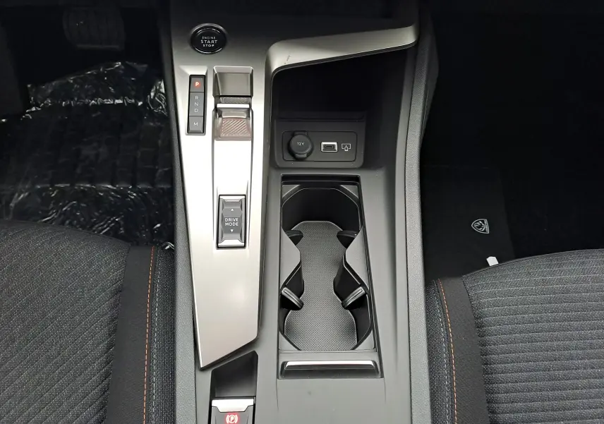 Vue plongeante sur la console centrale de la Peugeot 308 2025, avec levier de vitesses électronique et porte-gobelets.
