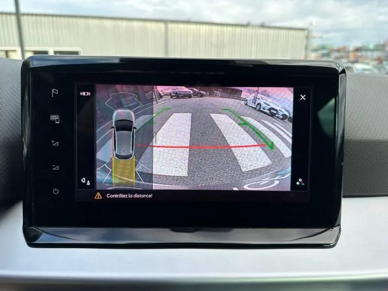 Écran de caméra de recul du SEAT IBIZA 1.0 TSI 115cv FR 2025, vue arrière avec marquages au sol et véhicules stationnés.