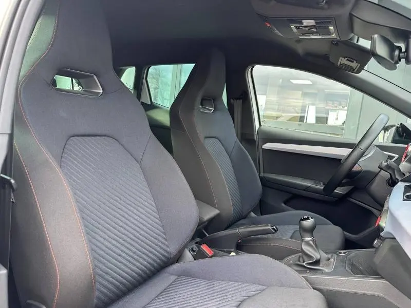 Vue intérieure côté gauche montrant les sièges sport noirs avec surpiqûres rouges et levier de vitesse manuel d'une SEAT Ibiza 2025.