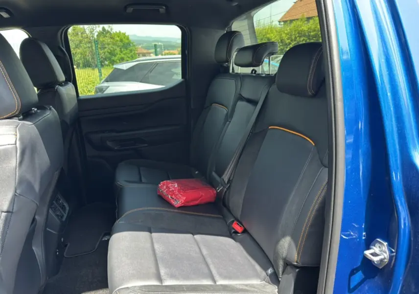 Vue intérieure côté droit sur la banquette arrière en cuir noir avec surpiqûres orange du Ford Ranger Wildtrak bleu lightning.
