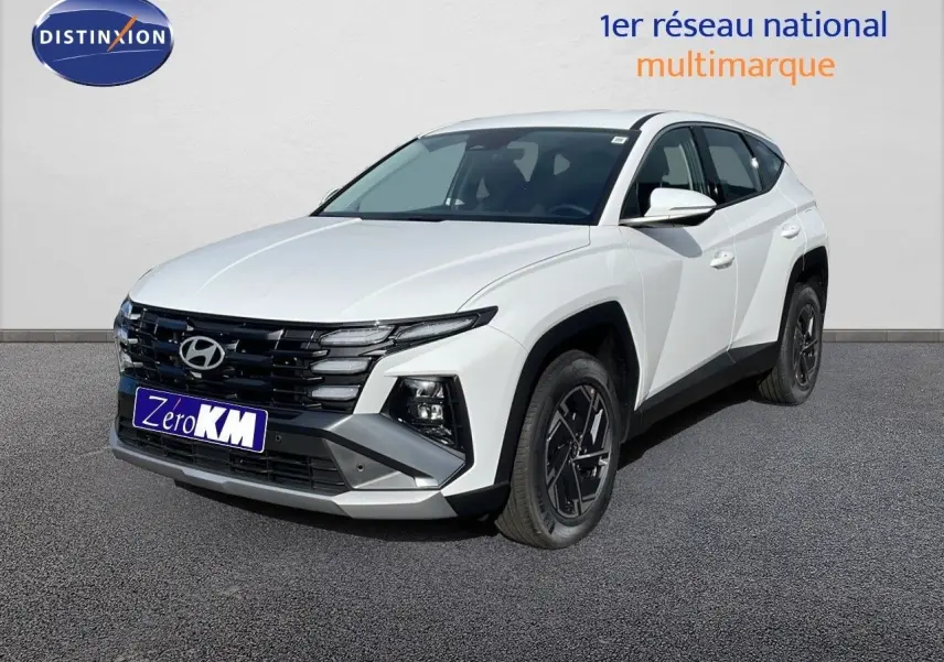 Hyundai Tucson blanc atlas en 3/4 avant droit, SUV hybride avec calandre noire et jantes bi-ton.