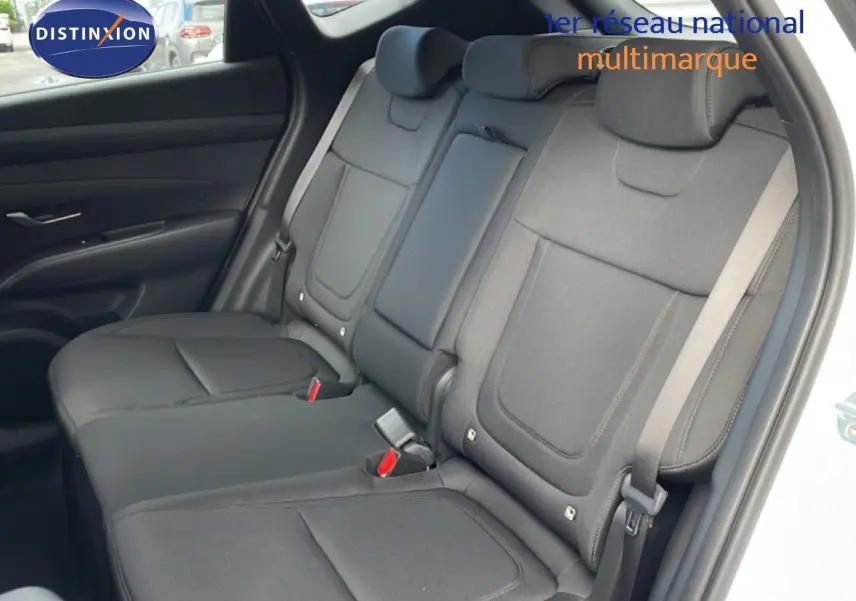 Vue intérieure sur les sièges arrière en tissu noir du Hyundai Tucson blanc Atlas, avec ceinture de sécurité visible côté droit.