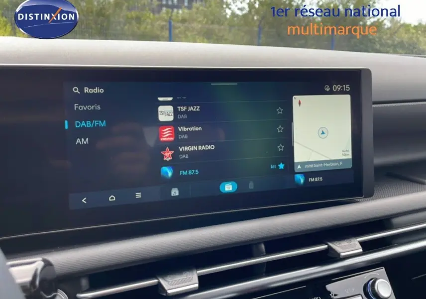Vue rapprochée de l'écran multimédia du Hyundai Tucson blanc Atlas, affichant la radio DAB/FM et la navigation.