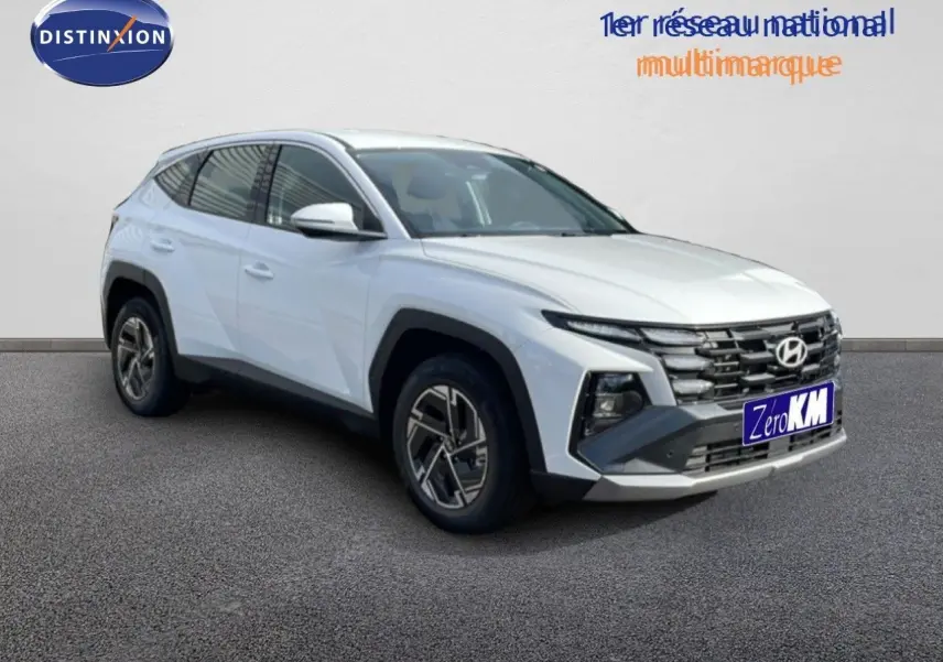 Hyundai Tucson blanc atlas en 3/4 avant droit, mettant en valeur sa calandre distinctive et ses jantes bi-ton.