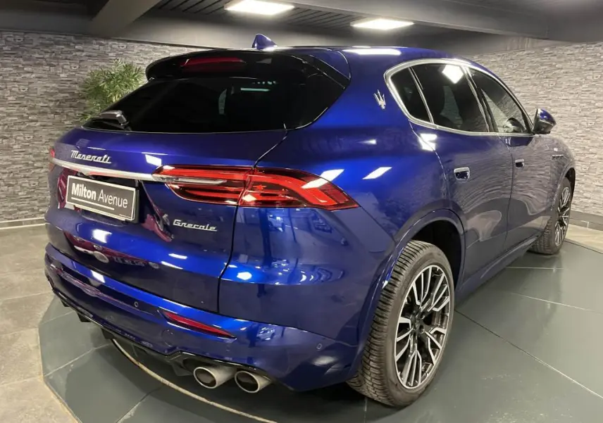 Vue 3/4 arrière droite du Maserati Grecale bleu avec jantes noires et double sortie d'échappement chromée.