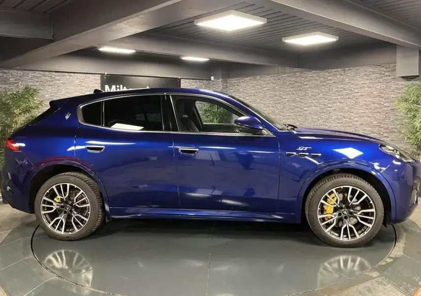 Vue latérale droite d'un Maserati Grecale bleu avec étriers de freins jaunes et jantes forgées 20 pouces gloss black.