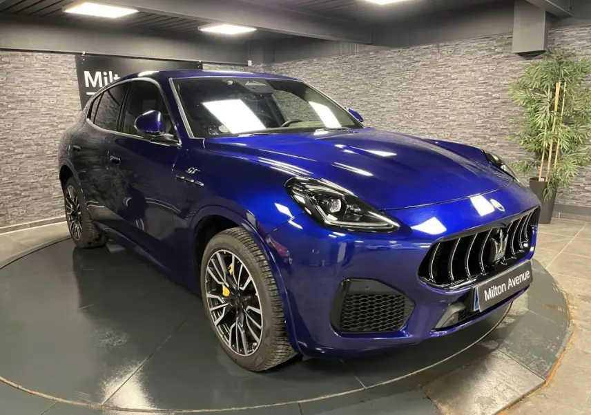 Vue 3/4 avant d'un Maserati Grecale bleu avec étriers de freins jaunes et jantes noires forgées en showroom.
