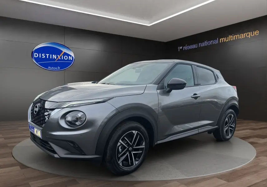 Nissan Juke Full Hybrid gris squale en 3/4 avant droit, avec jantes alliage noires et calandre distinctive.