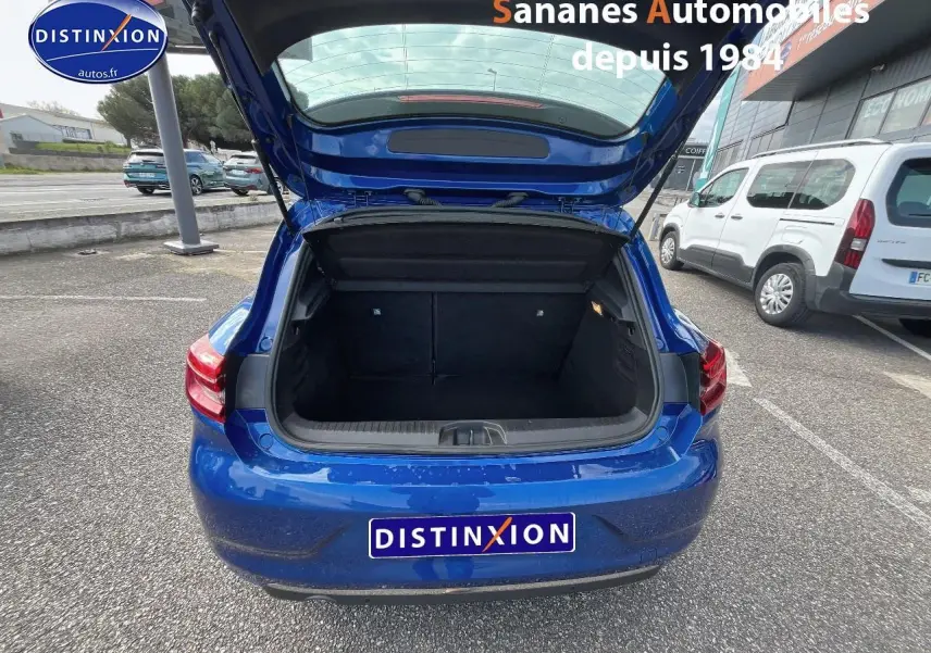 Vue arrière de la Renault Clio 1.0 Tce Intens 2021 en Bleu Iron avec coffre ouvert sur parking extérieur.