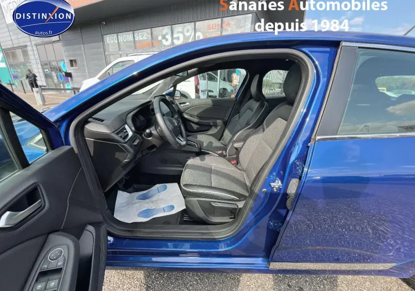 Vue latérale gauche sur l'intérieur d'une Renault Clio Bleu Iron 2021, avec sièges en velours et cuir synthétique noir.