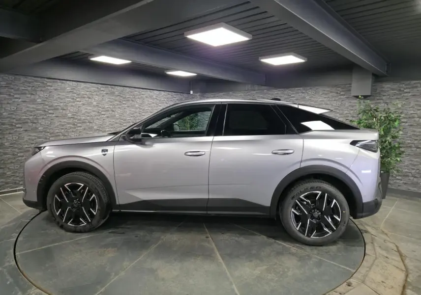 Peugeot 3008 gris en profil droit dans un showroom, avec jantes alliage noires et toit noir contrasté.