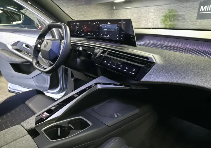 Vue intérieure côté conducteur du Peugeot 3008 gris 2025, avec tableau de bord numérique panoramique et console centrale design.