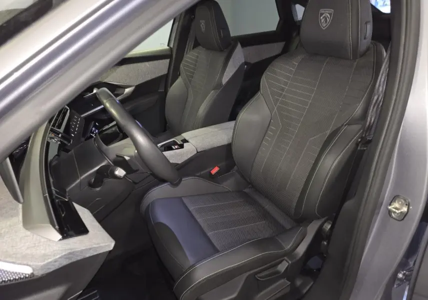 Vue intérieure côté conducteur du Peugeot 3008 gris 2025, sièges tissu et cuir avec logo GT brodé sur appuie-tête.