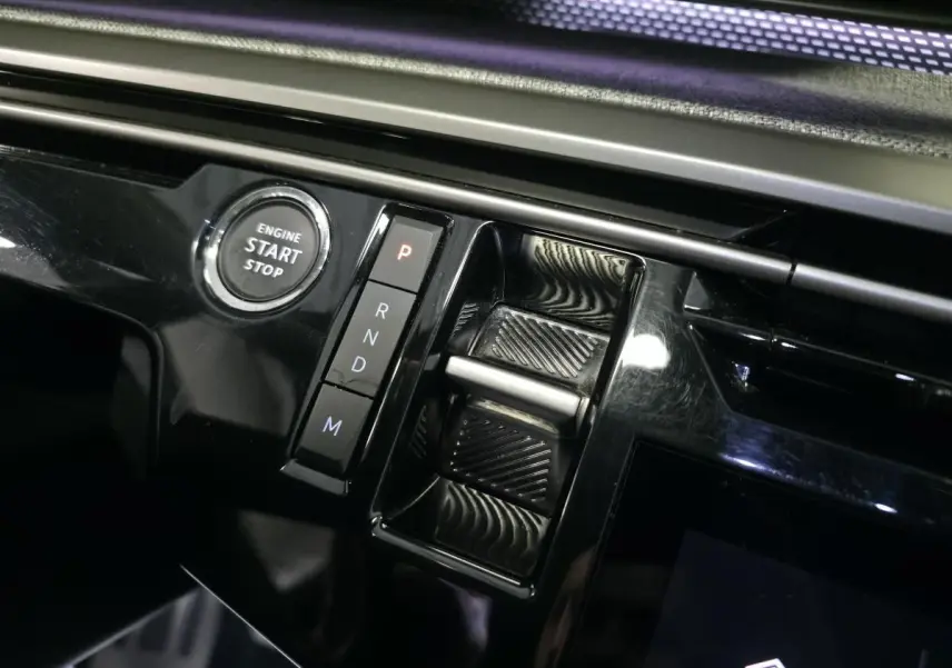 Gros plan sur la console centrale noire brillante du Peugeot 3008 2025 avec bouton start/stop et sélecteur de boîte automatique.