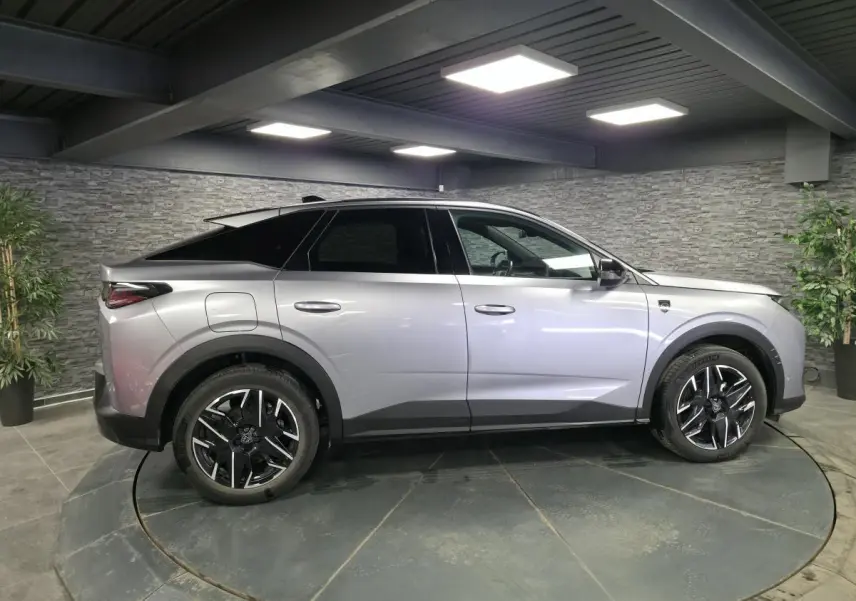 Vue latérale droite d’un Peugeot 3008 gris métallisé 2025 avec jantes alliage noires et toit noir contrasté.