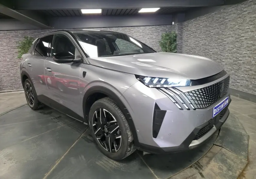 Peugeot 3008 gris en 3/4 avant droit, avec calandre noire à motif géométrique et feux LED griffés.