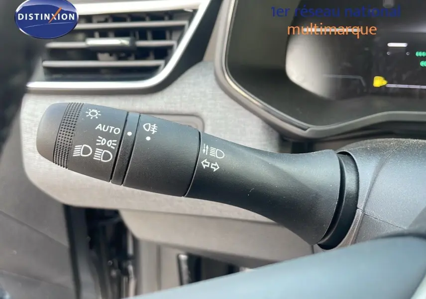 Gros plan sur la commande des feux d’un Renault Clio gris schiste, intérieur tissu gris-noir visible en arrière-plan.