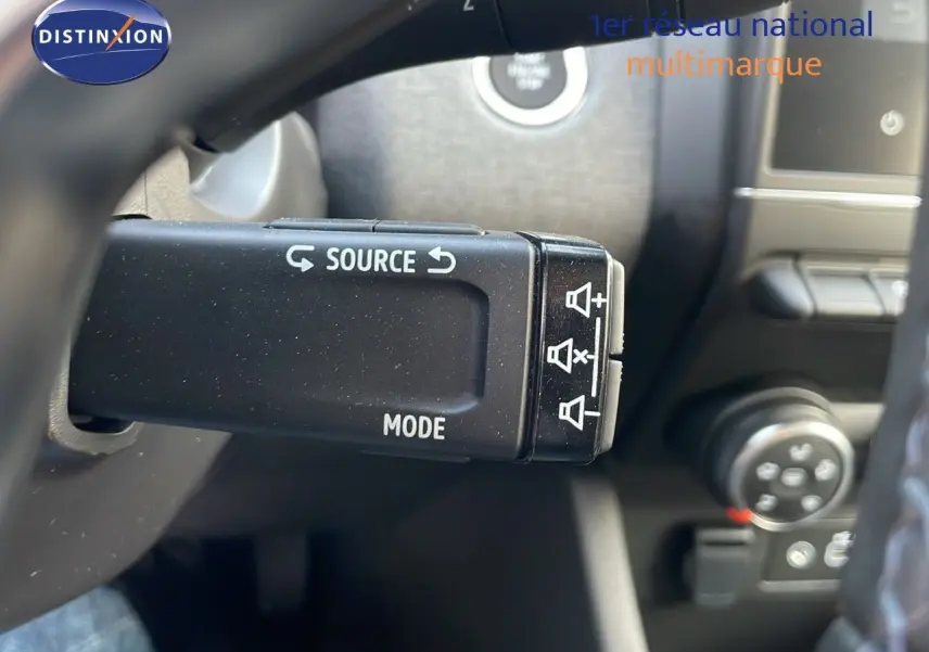 Gros plan sur la commande au volant de la Renault Clio 2025, avec boutons source et mode visibles en intérieur gris noir.