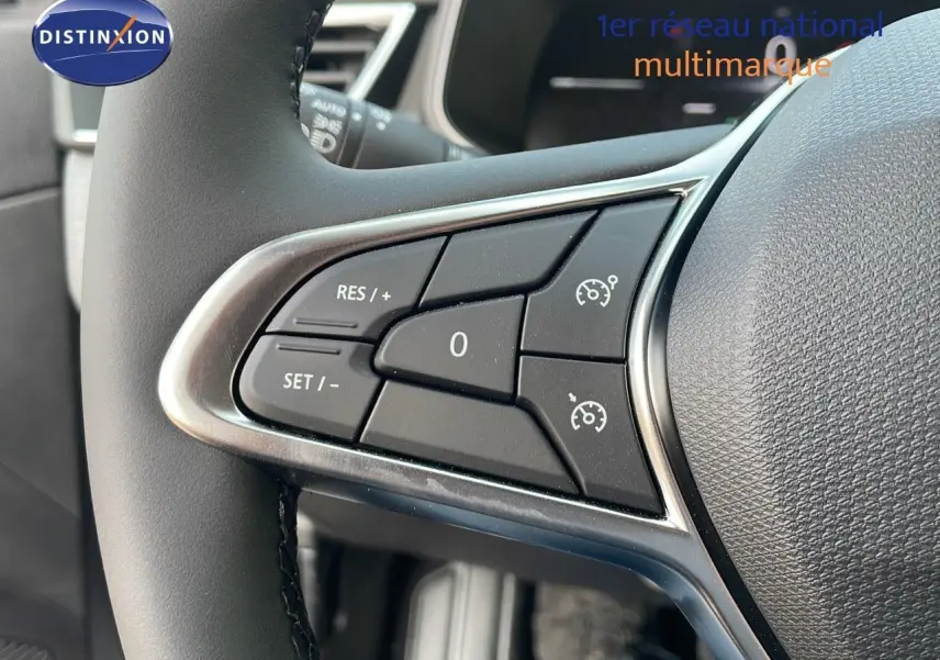 Gros plan sur les commandes de régulateur de vitesse au volant cuir d'une Renault Clio gris schiste métal, intérieur gris-noir.