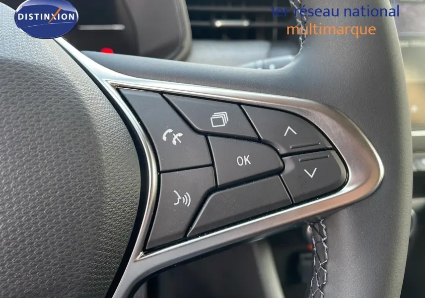 Gros plan sur les commandes au volant cuir de la Renault Clio 2025, finition gris schiste métal, boutons multifonctions visibles.