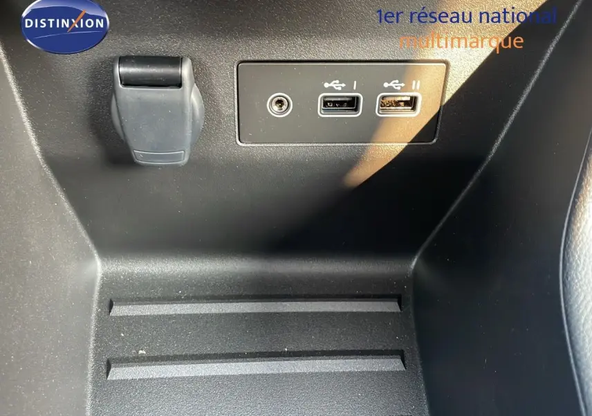 Détail intérieur montrant les ports USB et prise auxiliaire sur la console centrale d’une Renault Clio gris schiste 2025.