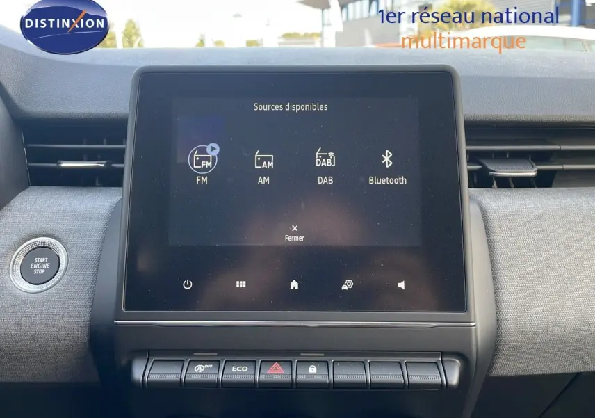 Tableau de bord de Renault Clio 2025, écran tactile central affichant les sources audio, finition tissu gris clair.
