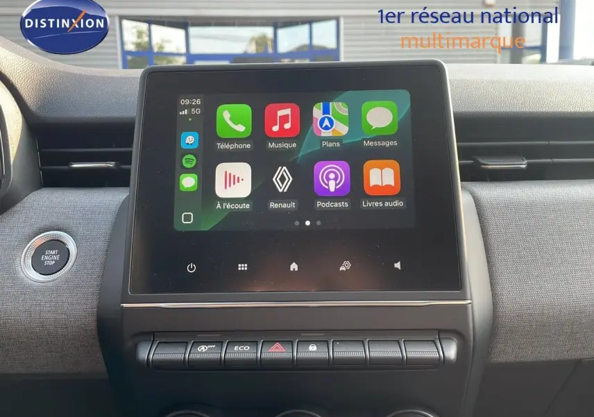 Vue rapprochée de l’écran tactile central de la Renault Clio gris schiste, avec commandes et bouton start/stop visibles.