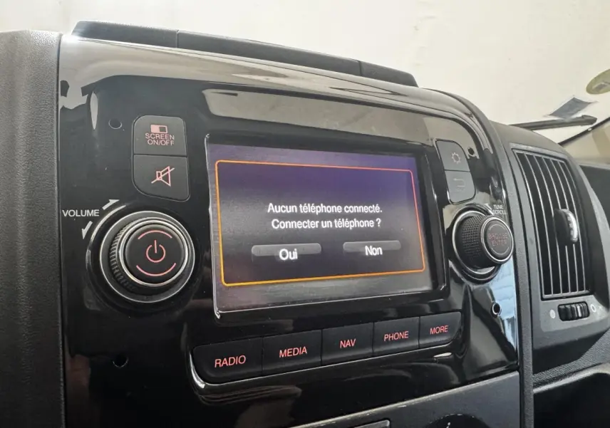 Gros plan sur l’écran tactile multimédia noir du tableau de bord du Citroën Jumper blanc, affichant une connexion téléphone.