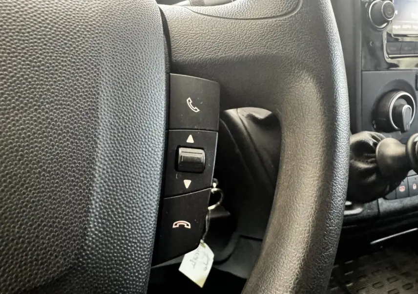 Gros plan sur le volant multifonctions noir du Citroën Jumper 33 L1H1, avec commandes d’appel intégrées.