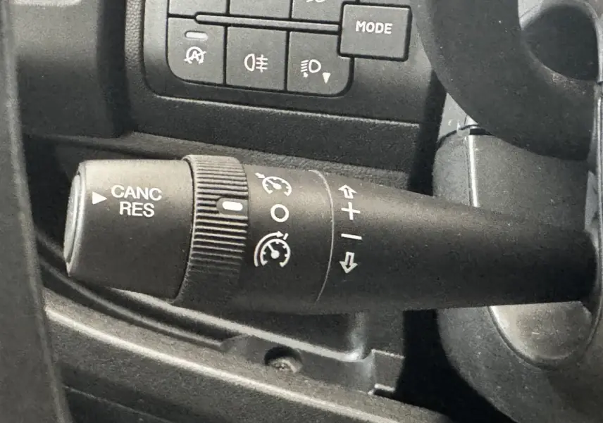 Gros plan sur la commande de régulateur de vitesse à gauche du volant dans l’habitacle du Citroën Jumper blanc 2023.