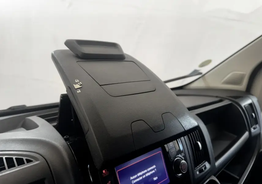 Vue intérieure rapprochée du tableau de bord noir du Citroën Jumper 2023 avec écran tactile et rangement ouvert.