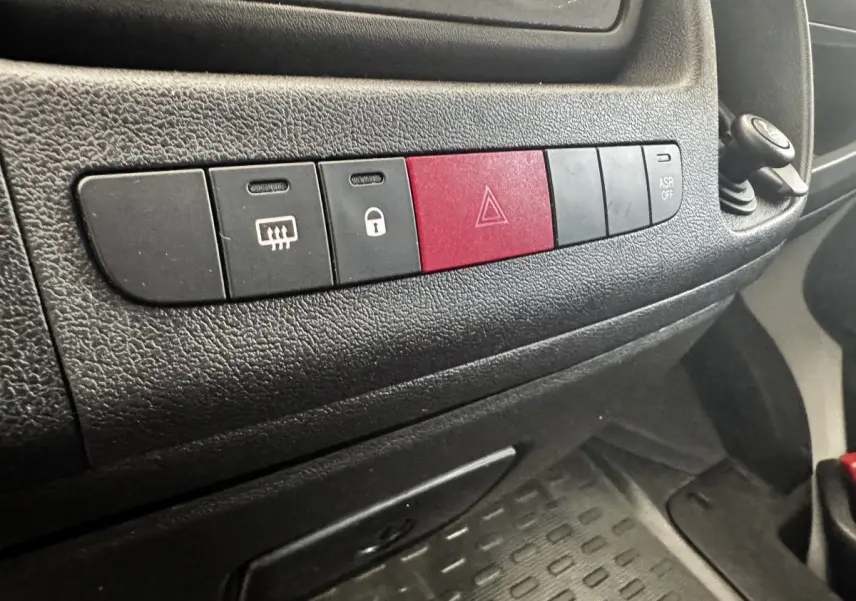 Gros plan sur la rangée de boutons noirs et rouge du tableau de bord du Citroën Jumper 2023, intérieur noir.