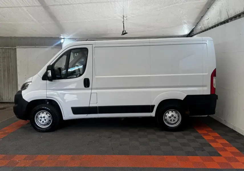 Vue de profil côté gauche d’un fourgon blanc Citroën Jumper 33 L1H1 avec jantes acier et protections noires.