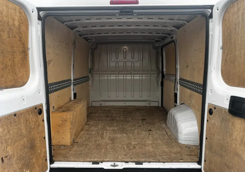 Vue arrière intérieure du Citroën Jumper blanc 33 L1H1 avec cloison pleine et revêtement bois du coffre.