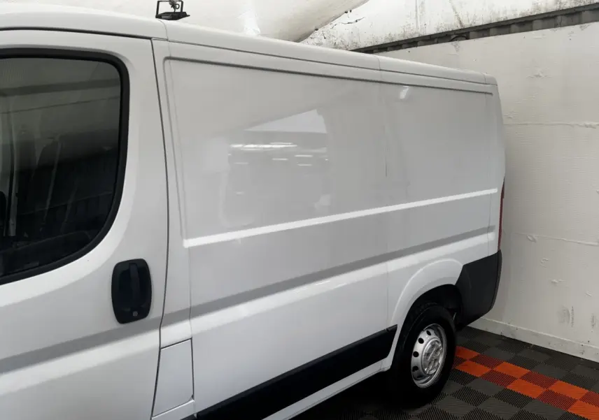 Vue latérale droite d’un utilitaire blanc Citroën Jumper 33 L1H1 avec porte coulissante et jante acier.