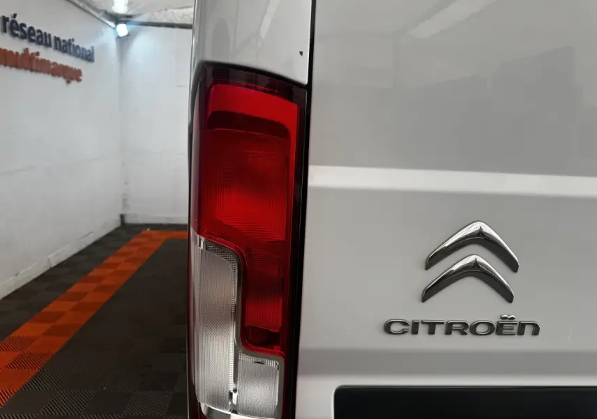 Gros plan sur le feu arrière gauche d’un utilitaire blanc Citroën Jumper, avec logo visible sur la porte arrière.