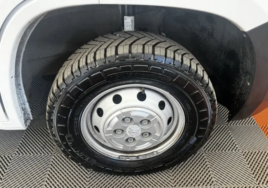 Gros plan sur la roue avant gauche acier d’un Citroën Jumper blanc, montrant le pneu Michelin et l’aile du véhicule.