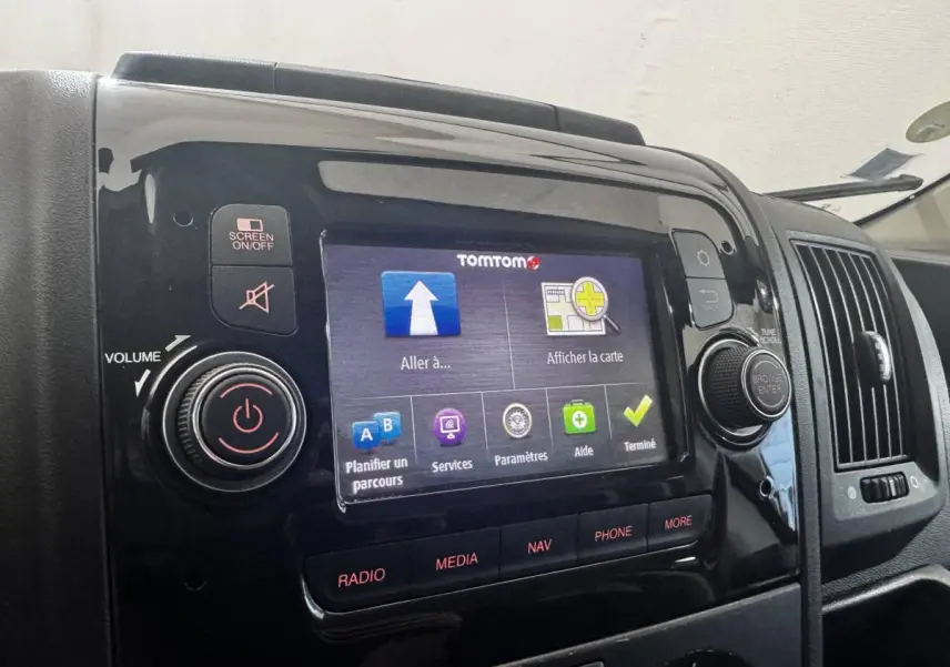 Écran tactile central allumé avec interface TomTom, tableau de bord noir brillant du Citroën Jumper blanc 2023.