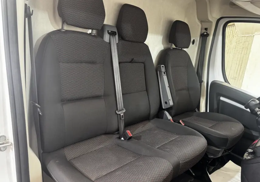 Vue intérieure côté conducteur du Citroën Jumper blanc 2023, montrant les sièges avant noirs avec détails rouges.
