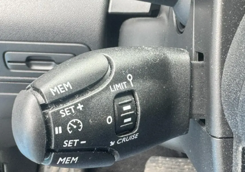 Gros plan sur la commande de régulateur de vitesse noire dans l'habitacle du Citroën C3 Aircross gris acier.