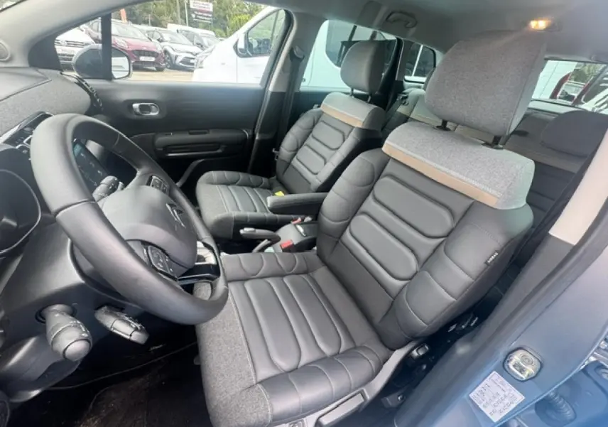 Vue intérieure côté conducteur de la Citroën C3 Aircross 2024 avec sièges bi-matière gris et volant cuir noir.