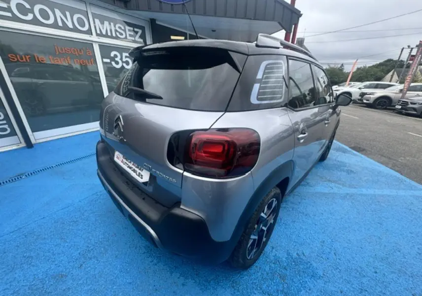 Vue 3/4 arrière droite du Citroën C3 Aircross gris acier avec toit noir et feux arrière foncés.