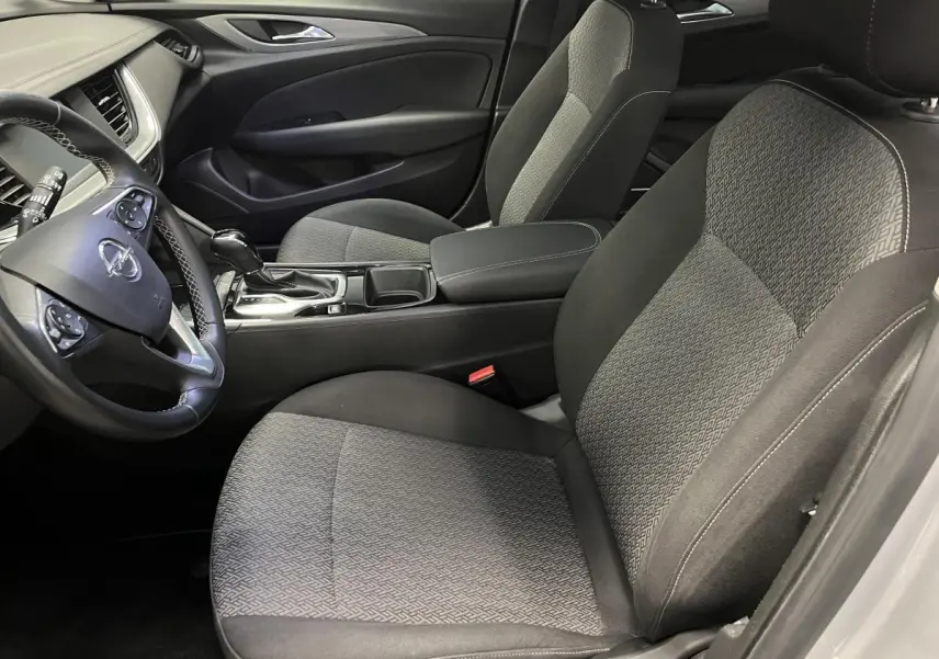Intérieur avant droit de l’Opel Insignia gris, sièges tissu anthracite et volant cuir multifonctions visible.