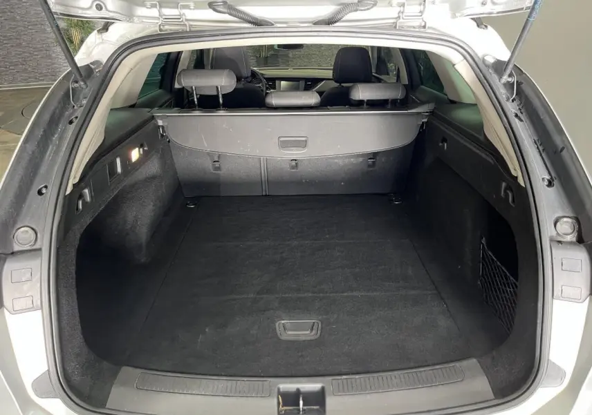 Coffre ouvert vu de l'arrière d'une Opel Insignia Sports Tourer gris, montrant un espace de chargement propre et spacieux.