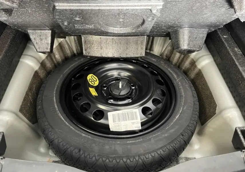 Roue de secours noire dans le coffre de l'Opel Insignia Sports Tourer gris, vue en plongée.