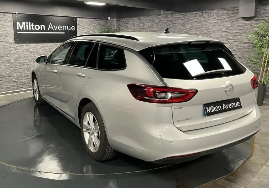 Vue 3/4 arrière droite d'une Opel Insignia Sports Tourer gris métallisé avec vitres surteintées en showroom.
