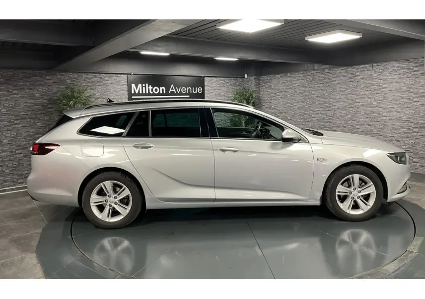 Profil côté gauche d'une Opel Insignia Sports Tourer gris métallisé dans un showroom avec jantes alliage 5 branches.
