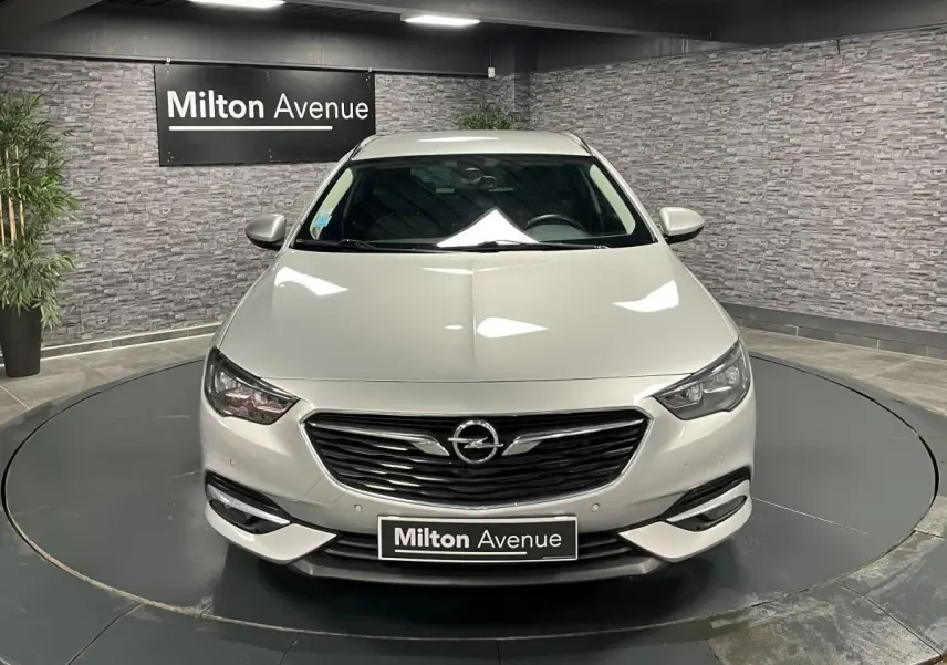 Opel Insignia Sports Tourer gris métallisé vue de face dans un showroom avec calandre noire et phares LED.